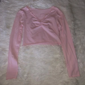 Rosa croppad topp - Säljer en söt rosa croppad topp med långärmad design och v-ringning. Använd fåtal gånger 🥰