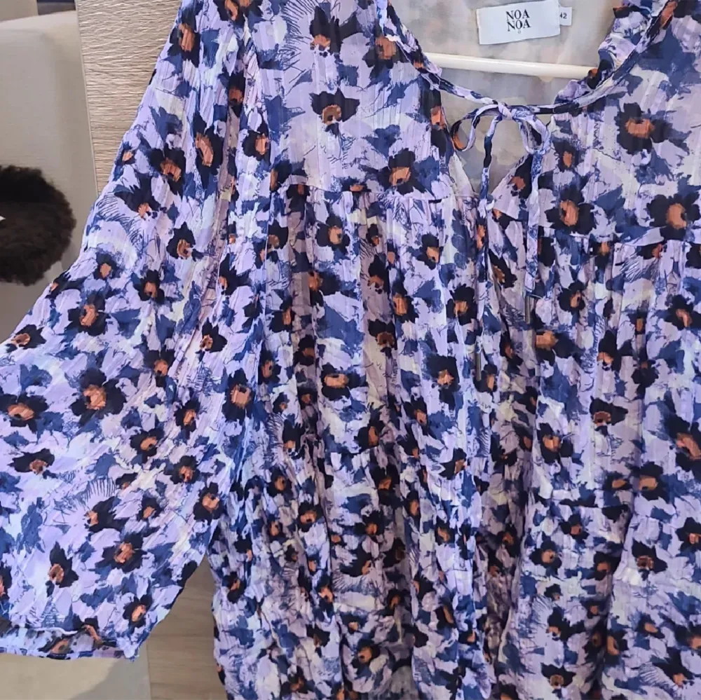 Tunn skön blommig blus från Noa Noa i stlk 42/L. Luftigt material perfekt för sommaren och lila blommig design. Snöre och knapp framtill och rush vid nacken. Nypris ca 700kr, knappt använd.. Puserot.