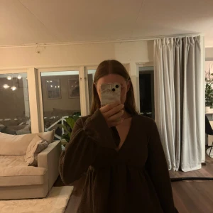 Brun långärmad topp från Gina - Säljer en brun långärmad topp från Gina med v-ringning och en lös passform. Toppen har en lätt ribbad struktur och är perfekt för en avslappnad stil. Passar bra till jeans eller kjol för en enkel look.