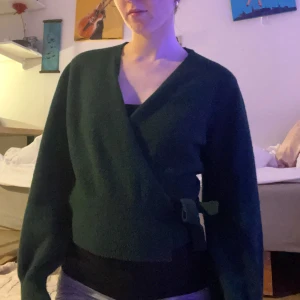 Grön omlottkofta - Säljer en mysig grön omlottkofta med knytband i midjan. Köpt på other stories för 800kr. Mycket bra skick som man kan se på bilden. 
