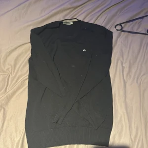 Svart tröja från J.Lindeberg - Säljer en stilren svart tröja från J.Lindeberg i storlek S. Tröjan är tillverkad i 100% merinoull och har långa ärmar. Perfekt för kyligare dagar. Liten logotyp på bröstet.