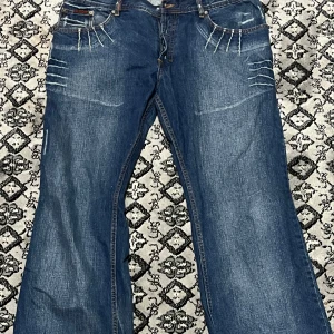 Blå jeans med slitningar - Snygga blå jeans med coola slitningar och kontrastsömmar. De har en klassisk femficksdesign och en flared passform