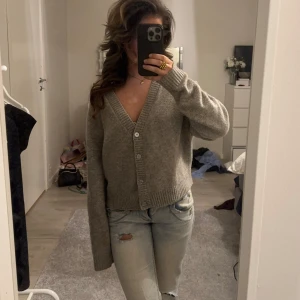 Grå kofta med knappar - Säljer en mysig grå kofta med v-ringning och knappar framtill. Köpte den här på Plick men har inte använt jätte många gånger! Den är lite nopprig men inget man tänker på så mycket. Den är storlek M men är liten i storleken så skulle säga att den sitter mer som S/XS (min vanliga storlek) 