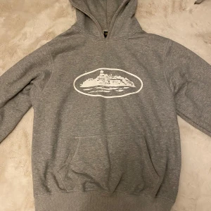 Grå hoodie med vitt tryck - Säljer en grå corteiz hoddie i storlek M. Inte så använd, ser väldigt fräsch ut och den är i bra skick och har bra kvalite. 