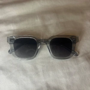 Grå Chimis 04 - Snygga solglasögon med transparent båge och fyrkantig form. Glasen är mörkt svarta och ger en cool kontrast mot den klara ramen. Perfekt accessoar för soliga dagar. Skriv innan köp!❤️