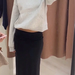 Svart ribbad långkjol - Snygg svart ribbad långkjol med en stilren design. Kjolen har en diskret slits på sidan som ger extra rörelsefrihet. Perfekt för en chic och avslappnad look.