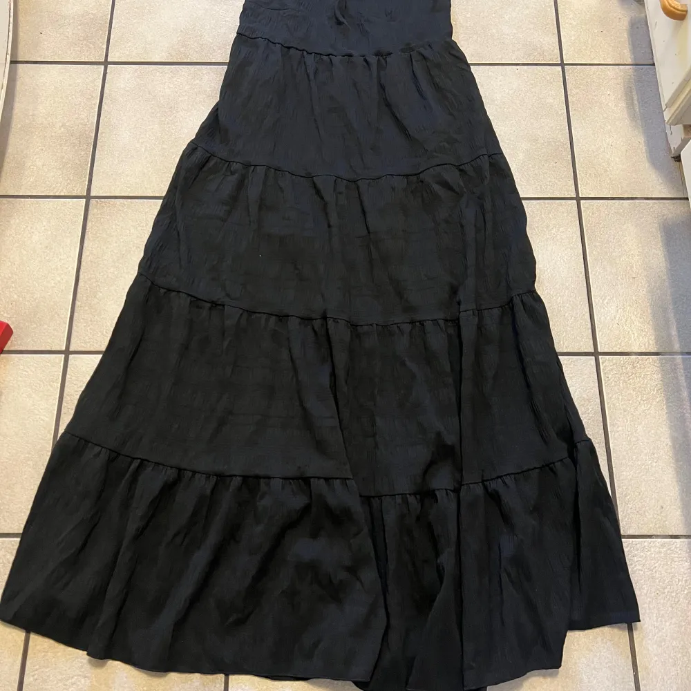 Säljer en elegant svart långklänning från Shein. Klänningen har en flödande design med flera lager och en elastisk midja för en bekväm passform. Perfekt för en stilren look.. Mekot.