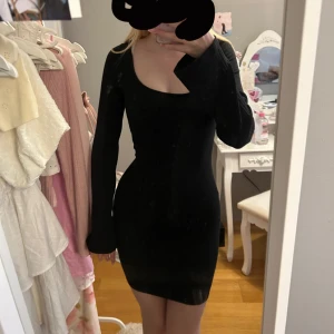 Svart tight klänning - Snygg svart klänning med långärmad design och en djup v-ringning. Perfekt för en kväll ute eller en speciell tillställning. 