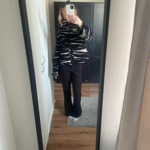 Svart och vit teddyjacka - Mysig svart och vit teddyjacka med zebramönster och dragkedja framtill. Jackan har långa ärmar och en hög krage för extra värme. Perfekt för kyliga dagar.