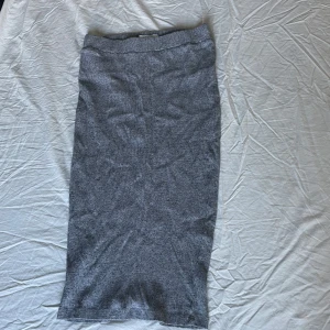 Grå kjol från Josefin Ekström från NA-KD - Snygg grå kjol från NA-KD. Kjolen har en ribbad textur och är perfekt för en stilren look. Den är knälång och passar bra till både vardag och festligare tillfällen.