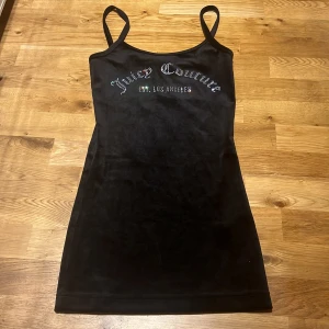 Svart sammetsklänning från Juicy Couture - Säljer en svart sammetsklänning från Juicy Couture med smala axelband och broderad logga framtill. Klänningen har en figurnära passform och är kort i modellen. Perfekt för dig som gillar en klassisk och trendig look. Klänningen har aldrig använts, lapp saknas!