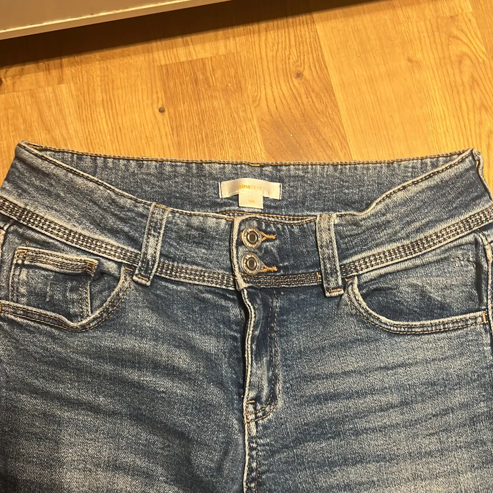 Säljer ett par klassiska blå bootcut jeans från Gina Tricot i storlek 158. Jeansen har fem fickor, dragkedja och knapp framtill samt snyggt utsvängda ben. Perfekta för dig som gillar en tidlös denimlook.. Farkut & Housut.