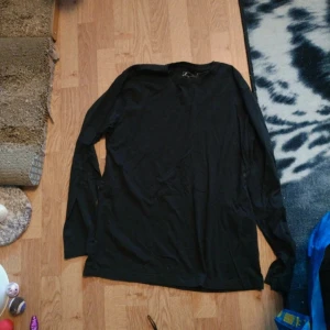 Svart långärmad tröja från H&M - En enkel svart långärmad tröja från H&M. Tröjan har rund halsringning och är tillverkad i ett mjukt material som passar perfekt till vardags. Stilren och lätt att matcha med andra plagg.