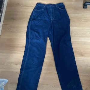 Mörkblå raka jeans - Säljer ett par mörkblå jeans med raka ben och klassiska fickor både fram och bak. Jeansen har normal passform och tydliga kontrastsömmar. Perfekta för en avslappnad stil.