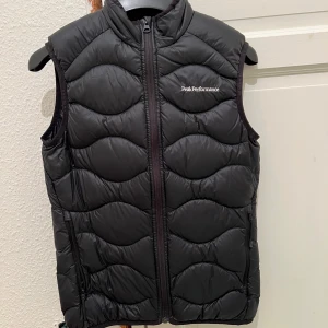 Svart dunväst från Peak Performance - Säljer en svart dunväst från Peak Performance. Västen har en dragkedja framtill och är perfekt för kyligare dagar. Den är stilren och lätt att matcha med andra plagg. Som ny, säljer pga för liten😊