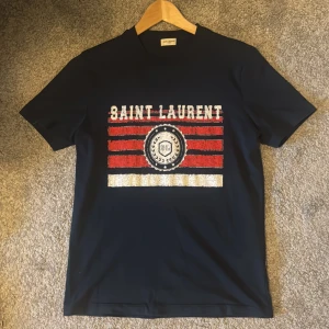 Saint Laurent t shirt - Säljer nu denna högt eftertraktade t shirten från Saint Laurent. Storlek S, passar M. Nyskick!! Nypris cirkus 4k. Bevis på äkthet finns. Tveka inte på att skriva vid minsta lilla fråga eller fundering! 🤩pris kan diskuteras men kommer ignorera orimliga bud!!!!