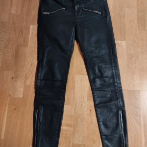 Svarta skinny jeans från Gina Tricot - Snygga svarta skinny jeans från Gina Tricot med dragkedjedetaljer vid fickorna och bensluten. Perfekta för en stilren look. Tillverkade i en blandning av bomull och polyester för en bekväm passform.