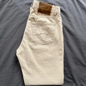 Beige jeans från Jacob Cohen - Snygga beige jeans från Jacob Cohen, modell 610. Tillverkade av exklusivt japanskt tyg med italienskt hantverk. De har en klassisk design med knappar och en stilren look. Perfekta för dig som vill ha något unikt och stilrent i garderoben. Nypris 4000kr