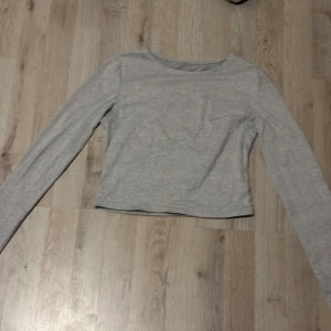 Grå långärmad tröja - Säljer en enkel och stilren grå långärmad tröja. Perfekt för en avslappnad look. Tröjan har en rund hals och är gjord i ett mjukt material.