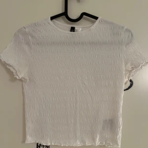 Vit ribbad kortärmad topp från H&M - Vit ribbad topp med korta ärmar från H&M i storlek S. Toppen har en elastisk struktur som ger en bekväm passform. Använd ytterst få gånger.
