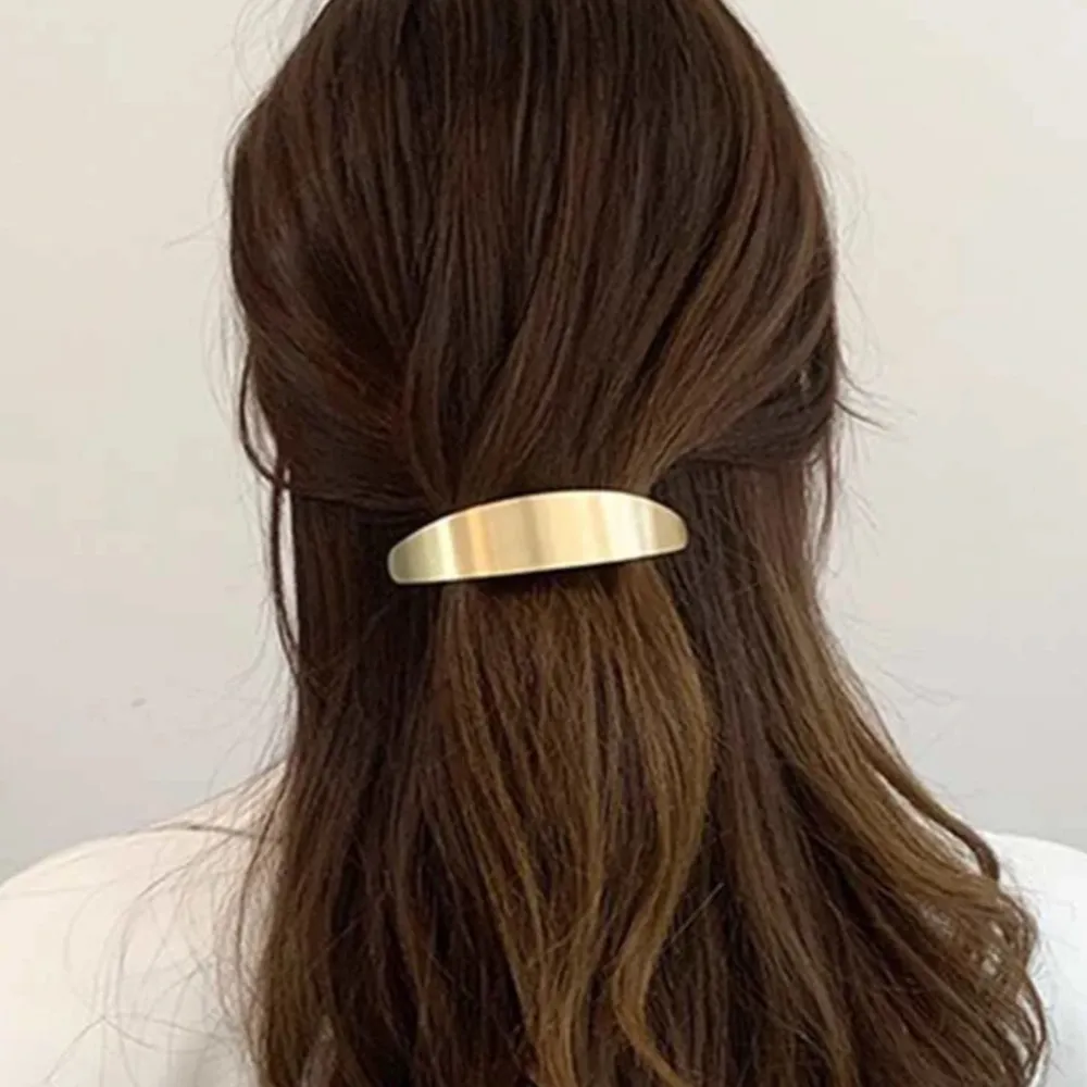 Snygg och stilren hårklämma i guld med en slät, böjd design. Perfekt för att hålla håret på plats med en touch av elegans. Passar både till vardag och festliga tillfällen.. Asusteet.