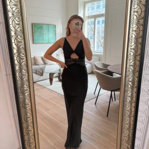 Svart långklänning med spetsdetaljer - Aldrig använd, prislapp kvar.