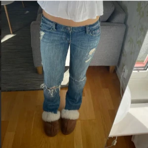 Blå jeans med slitningar - Snygga bootcut low-waist jeans från Hollister, midjemått mått: 38cm rakt över och inerbenslängd: 82 cm rakt ner. Köpte av en annan säljare men de var tyvärr för små.😚