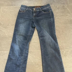 Blå jeans från Dromedar - Snygga blå jeans från Dromedar. Märkesdetaljer på bakfickorna. Fina knappar och mönster på fickorna. 