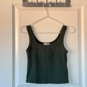 Mörkgrön ribbad topp - Mörkgrön ribbad topp från Gina Tricot. Toppen har breda axelband och en rundad halsringning. Strl 158/164 men passar XS skulle jag säga, väldigt stretchigt material 