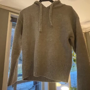 Grå stickad hoodie från Zara - Säljer en mysig grå hoodie från Zara. Tröjan har en luva med dragsko och ribbade muddar vid ärmslut och nederkant. Perfekt för kyliga dagar! Den är ganska nopprig men man kan få bort det.