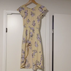 Gul blommig klänning från Lindex - Charmig gul klänning från Lindex med lila blommönster. Klänningen har korta ärmar och en luftig passform, perfekt för varma dagar. Den är tillverkad i ett lätt och bekvämt material. Den har även inbyggd shorts. Skriv gärna om du vill ha mer information om klänningen 😊🌼.