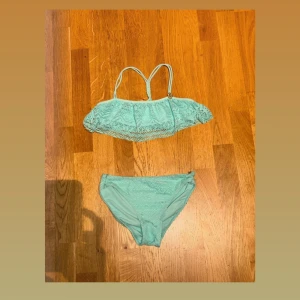 Ljusblå bikini med spetsdetaljer - Supersöt ljusblå bikini med volang och spetsdetaljer. Toppen har smala axelband och ett snyggt virkat mönster över bysten. Bikinitrosan har matchande spets och klassisk passform. Perfekt för strandhäng och poolparty!🌊☀️🏝️