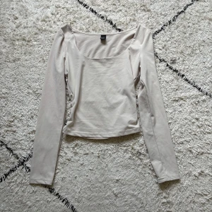 Beige långärmad topp från SHEIN - Säljer en stilren beige långärmad topp från SHEIN i storlek XS Petite. Toppen har en snygg, något croppad passform och en bred, rundad urringning. Perfekt att matcha med jeans eller kjol för en clean look.