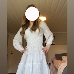 Vit långklänning med smock i midjan - Vit linne klänning från Chelsea, Det står ingen storlek i den, men den passar mig som kan ha både XS och S.   Den har inga fläckar och är i jätte fint skick. Köpte den till midsommar 2023, har använt den 3 gånger, nypris var omkring 500kr.  Säljer den nu eftersom den börjar bli lite kort för mig.  (Det är jag som har på mig den på bilden)