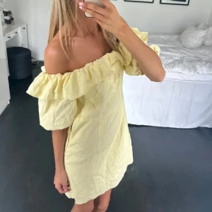 Gul offshoulder kortklänning - Söt ljusgul kortklänning med offshoulder och volangdetaljer. Klänningen har puffiga ärmar och en avslappnad passform, perfekt för varma dagar. Tillverkad i ett lätt bomullstyg som känns luftigt och bekvämt. Storlek s OBS kan posta senast idag och imorgon (17-18 juli) åker iväg sedan💓