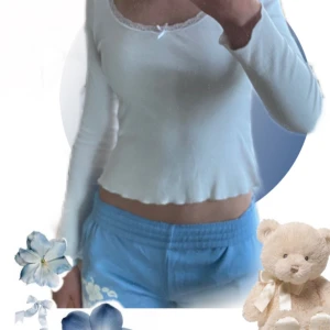 Coquette Vit långärmad topp med spets från BikBok - Supersöt vit långärmad topp från BikBok med ribbad struktur, spetskant runt urringningen och en liten rosett framtill. Toppen passar bra till både jeans och kjol. Perfekt för dig som gillar en feminin och trendig stil. Tröjan ser mestadels ny ut men har en defekt, se sista bilden tröjan har gulnat lite i armhålan av deo.