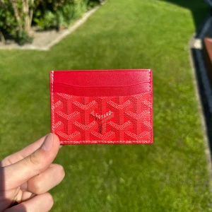 Röd Goyaard korthållare  - Säljer en snygg röd korthållare, nytt skick(har aldrig använts) den kommer med etikett och låda, skriv gärna om du har frågor eller andra funderingar! 