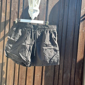 Svarta shorts med snörning - Snygga svarta shorts med elastisk midja och snörning framtill. Lätta och luftiga, perfekta för varma dagar. Klassisk modell med normal passform och sidfickor. Enkla att matcha med allt i garderoben.
