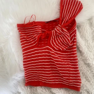Orange randig oneshoulder topp från Zara - Säljer en orange och vit randig oneshoulder topp från Zara. Materialet är stickat och ger en cool struktur. Perfekt för dig som vill sticka ut med en färgstark och trendig look. Strl M men passar också S