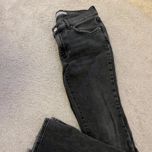Svarta/Grå lågmidjade jeans - Säljer ett par svarta/grå jeans med snyggt tvättad look. Jeansen har klassisk femficksdesign och är lågmidjade bootcut. Dom har gått upp lite på kanten där nere. 