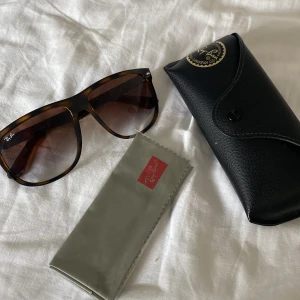 Ray-Ban bruna solglasögon - Snygga Ray-Ban RB4147 solglasögon i brunmelerad plast med stora, fyrkantiga bågar och bruna tonade glas. Klassisk logga på linsen och medföljande svart fodral och putsduk. Perfekt accessoar för en cool look.