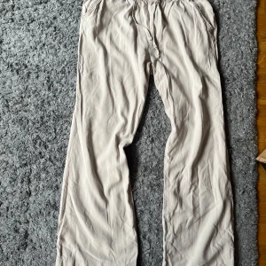 Beiga vida byxor med snörning 157 - Luftiga och sköna beiga byxor från 157 i storlek S. Vida ben och elastisk midja med snörning. Tillverkade i mjukt bomullstyg.