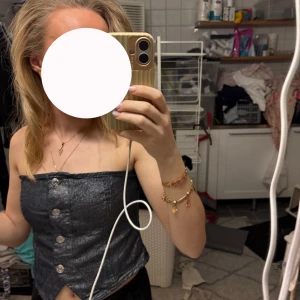 Glittertopp - Snygg blåglittrig tubtopp i jeansliknande material med silvriga knappar framtill. Toppen är axelbandslös och helt perfekt för fest.