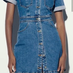 Kort jeansklänning med knappar - Snygg kort jeansklänning i blå denim med knappar framtill och korta ärmar. Klänningen har markerad midja, bröstfickor och klassisk skjortkrage. Perfekt för dig som gillar en cool och avslappnad stil. Storlek xs passar även S!