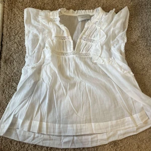 Vit blus  - Säljer denna superfina vita blusen med volanger ifrån neo noir. Den är i st Xs/S och den är i mycket bra skick så den knappt är använd. Ser lite gul ut i kameran men är vitare i verkligheten. Nypris är 599.