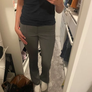 Grå kostymbyxor med bootcut - Snygga grå kostymbyxor med bootcut och hög midja. Byxorna har en klassisk passform som sitter tajt upptill och släpper ut vid bensluten. Perfekta för en clean och stilren look. Materialet känns mjukt och följsamt. Jag är 177 för längdreferns 