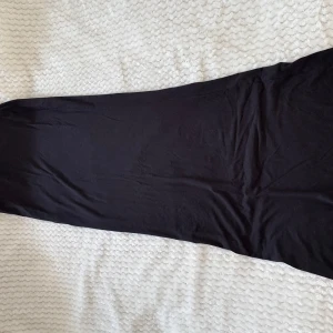 Svart långklänning i bomull - En stilren svart långkjol i mjukt bomullstyg från BikBok. Kjolen har en enkel och rak passform utan synliga detaljer eller mönster, perfekt för dig som gillar minimalistisk stil.