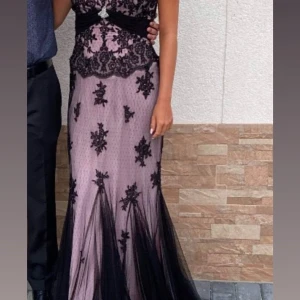 Lång spetsklänning i svart och lila - Säljer en elegant långklänning med lila bas och svart spetsdetaljer. Perfekt för bal eller fest. Använd fåtal ggr , mycket bra skick. Säljer för 2000 kr exklusive frakt. Passar en xs/s. 