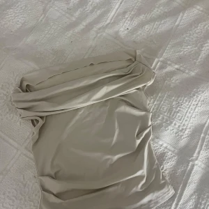 Beige bandeau tubtopp - Snygg beige bandeau tubtopp med draperad kant upptill.