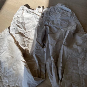 Beiga lågmidjade cargopants med resårmidja - (Pris går att diskutera💕)Säljer ett par beiga cargopants från Urban outfitters med resår i midjan och flera fickor. Byxorna har synliga sömmar , perfekta för en avslappnad och chill stil.